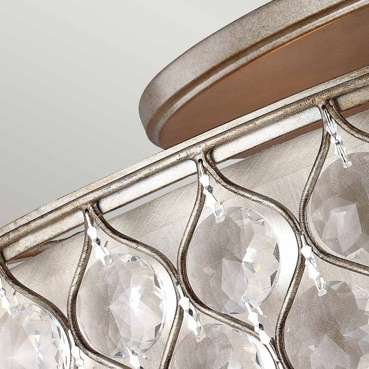 Presenting a close-up of the Lucia 6 Light Flush chandelier, adorned with Bauhinia crystals that hang elegantly in a circular arrangement, casting beautiful reflections. Its metallic frame boasts a burnished silver finish, enhancing the sophisticated appeal of this luxurious lighting fixture.