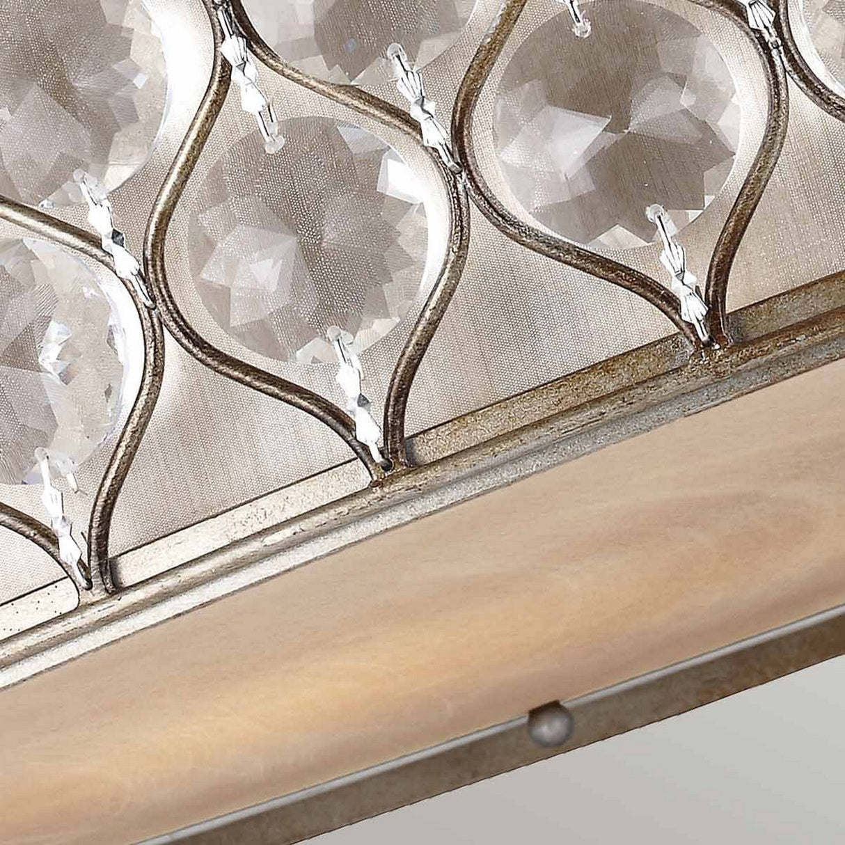 The Lucia 6 Light Flush - Burnished Silver chandelier, adorned with Bauhinia Crystals and a metallic frame, features a soft amber-colored base. Its burnished silver light enhances the crystals' patterned design, offering luxurious lighting with gentle reflections.