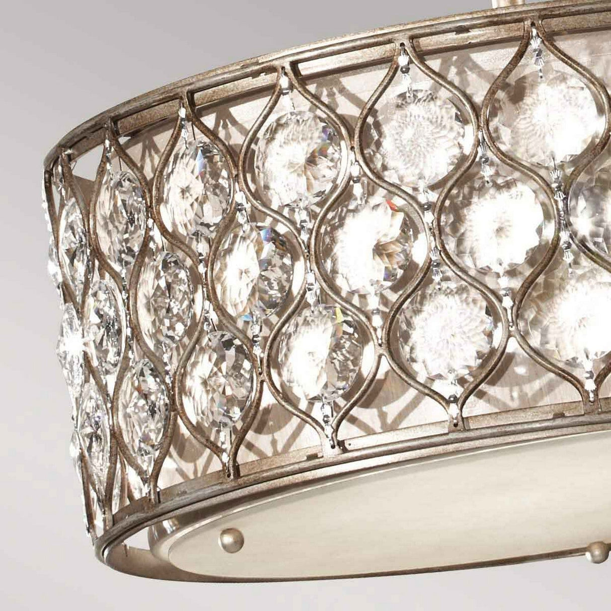 A close-up of the elegant Lucia 3 Light Chandelier - Burnished Silver, showcasing its circular arrangement with intricate latticework. This burnished silver structure is adorned with an array of sparkling Bauhinia crystals that capture and reflect the light, producing a luxurious and decorative effect.