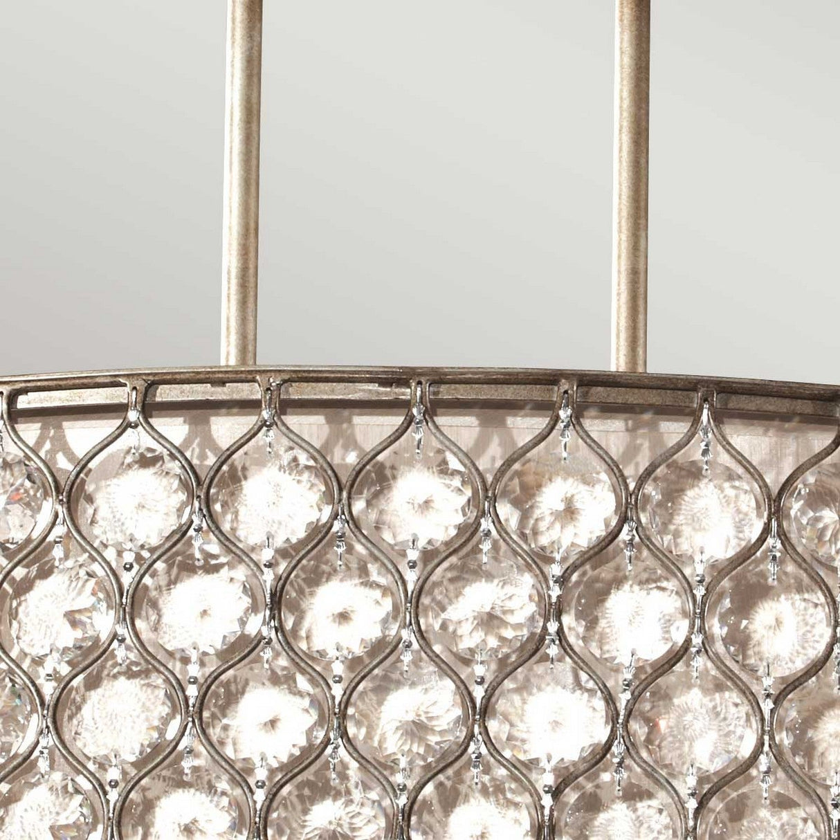 Close-up of the Lucia 3 Light Large Chandelier - Burnished Silver, showcasing a metallic frame with a repeating diamond pattern that encloses Bauhinia crystals. These crystals amplify the light, enhancing the chandelier's ornate design against a soft gray backdrop.