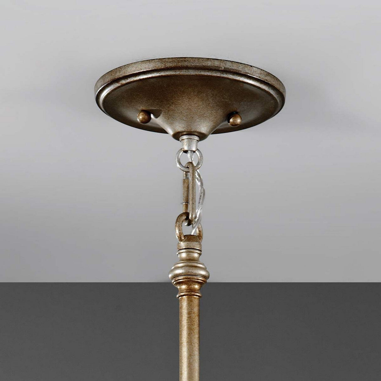 The Lucia 1 Light Pendant Light in burnished silver hangs from a light gray ceiling with a decorative metal chain and rod. Its design is rustic yet elegant, featuring Bauhinia crystals that add a touch of shimmer.