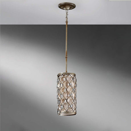 The Lucia 1 Light Mini Pendant in Burnished Silver showcases a decorative metal lattice design with glass insets. It features a burnished silver finish and is suspended from the ceiling by an elongated rod, set against a gray background.
