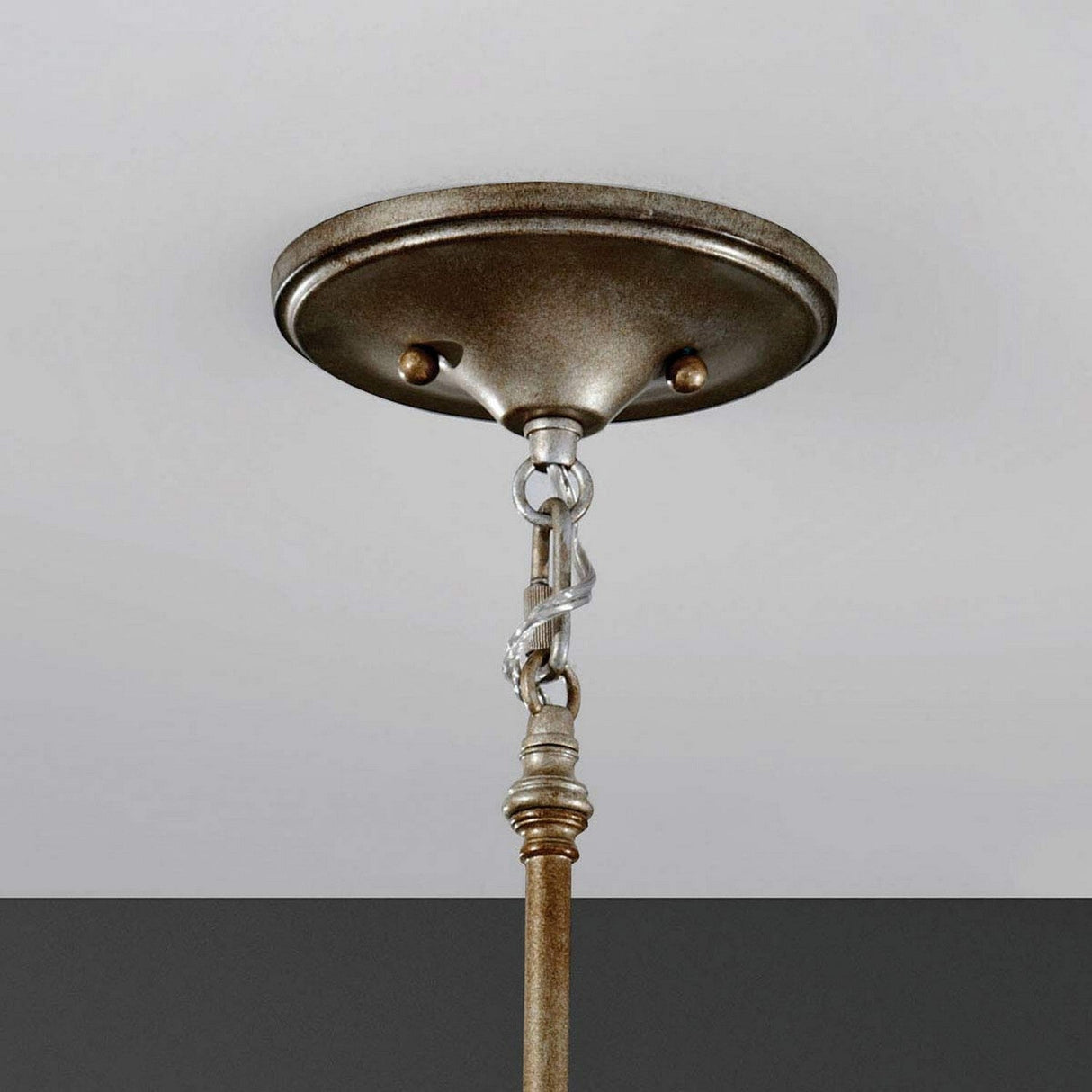 The Lucia 1 Light Mini Pendant in Burnished Silver, featuring a bronze ceiling canopy and a burnished silver metallic chain and rod, hangs against a two-tone wall, displaying sparkling Bauhinia crystals.