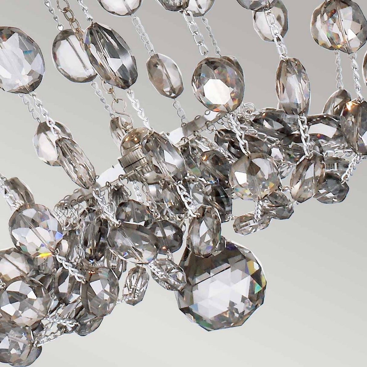 Detailed view of the Malia 3 Light Semi Flush - Polished Nickel chandelier, showcasing numerous faceted smoked crystal glass pendants suspended from intricate silver chains. The crystals catch the light, producing a sparkling effect against a backdrop of polished nickel.