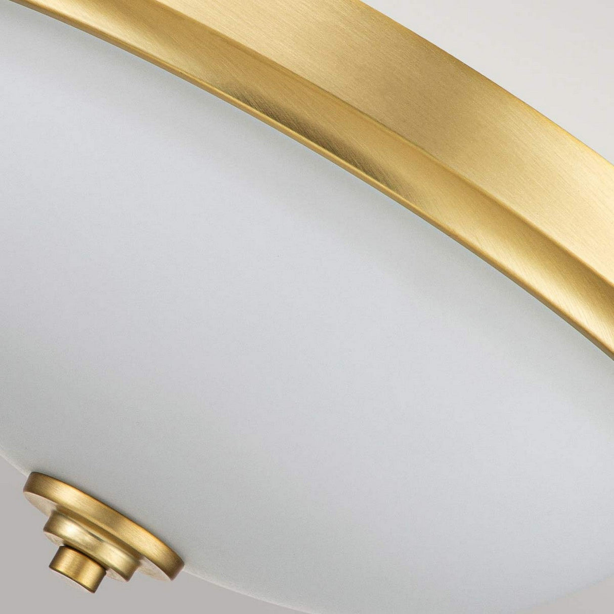 A close-up of the Malibu 2 Light Flush - Brushed Brass ceiling fixture features its opal-etched glass drum shade and elegant brushed brass rim. The image centers on the edge, showcasing its smooth design and sleek finish.