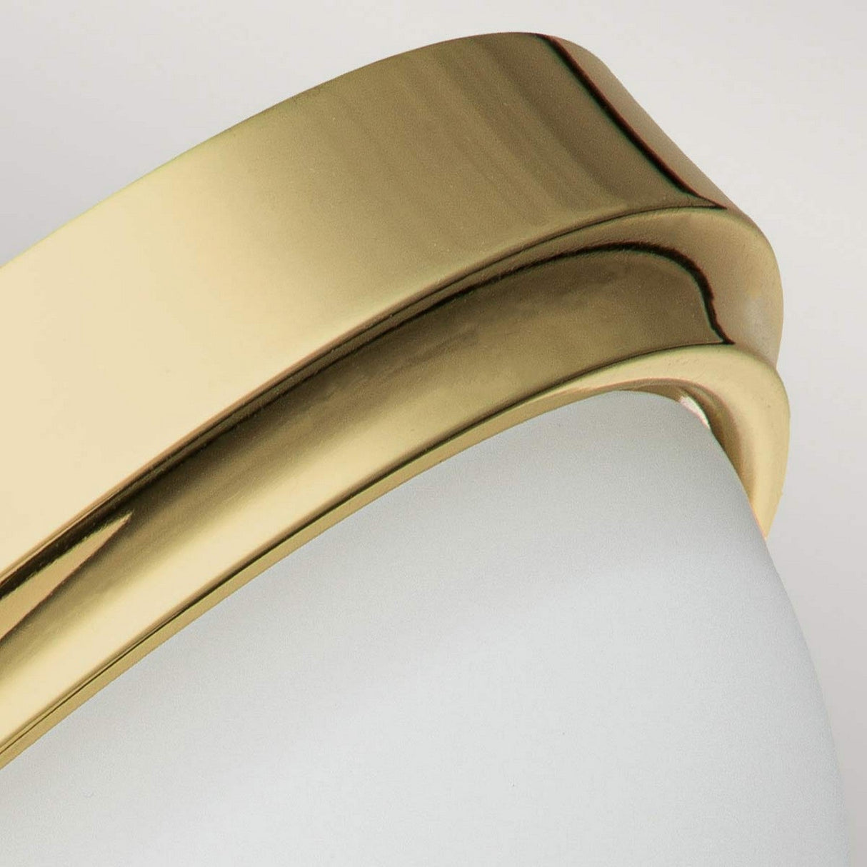 Close-up of the Malibu 2 Light Flush in polished brass, featuring a sleek and curved design. Its minimalist and elegant style provides ambient lighting, with the smooth surface beautifully contrasting against an opal-etched glass shade.