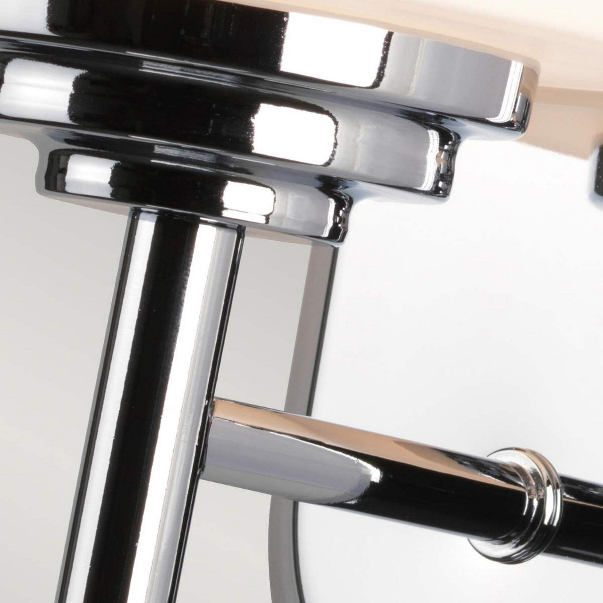 Close-up of the Malibu 1 Light Wall Light in polished chrome, reflecting light. The metal surface features smooth, polished curves and angles, presenting a sleek and modern appearance similar to opal-etched glass.