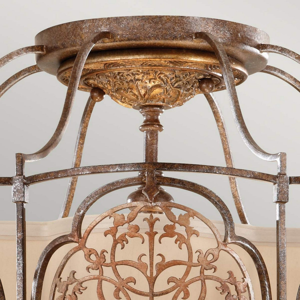Product Description: A close-up view of the Marcella 3 Light Semi Flush - Bronze showcases its vintage-style charm with intricate wrought iron detailing and a bronze finish. This design exudes exotic elegance, featuring graceful scrollwork and an ornamental centerpiece, all set against a soft, neutral background.