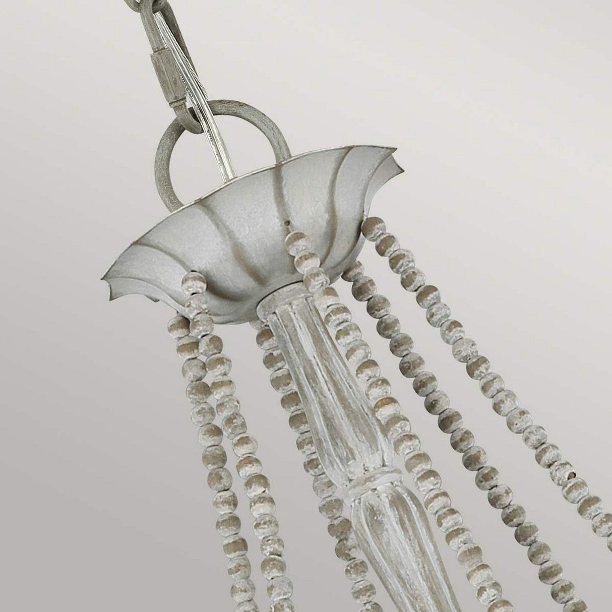 Close-up of the Maryville 6 Light Chandelier in Washed Grey, exuding rustic elegance with its metal top and cascading strands of round beads. It embodies French Country style, hanging gracefully from a hook and chain against a soft gray background.
