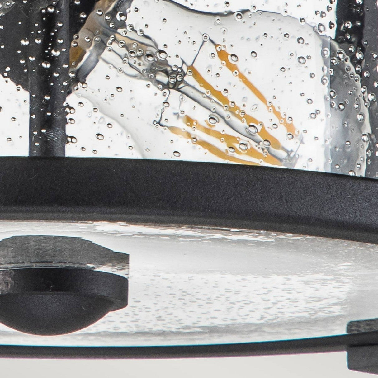 A close-up of the Merrill 2 Light Outdoor Flush - Black fixture highlights its sleek black finish and clear, bubble-textured glass that showcases multiple exposed filament bulbs inside.