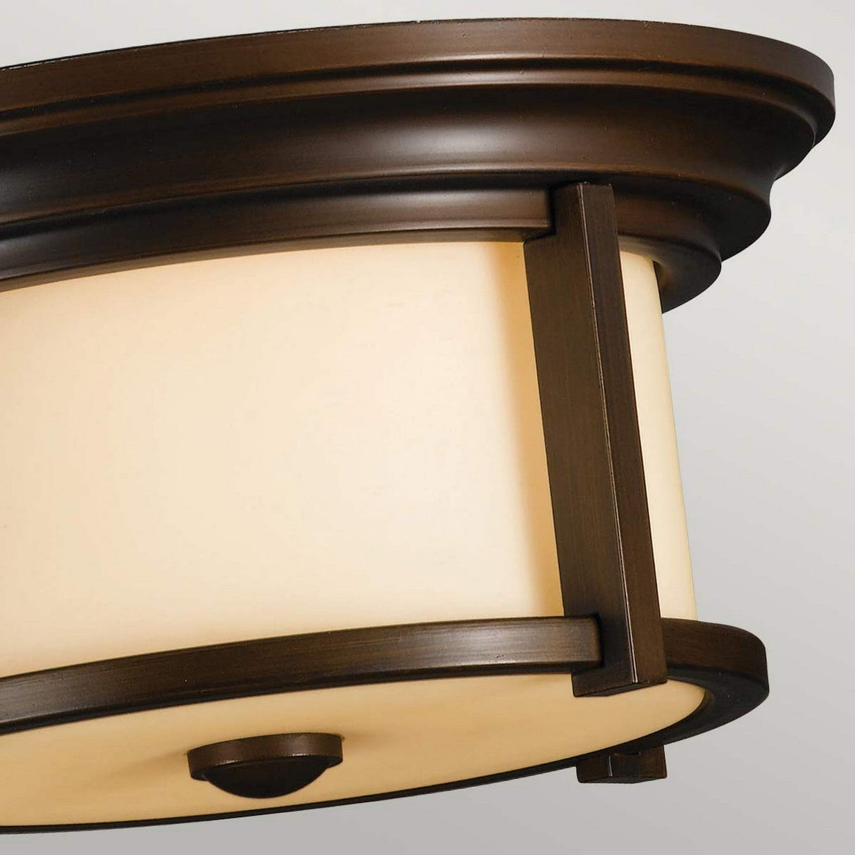 Close-up view of the Merrill 2 Light Outdoor Flush - Bronze, showcasing an IP44 rated ceiling light fixture with a heritage bronze frame and a frosted white glass shade. This design features a rounded shape that combines modern and classic elements, making it ideal for outdoor lighting against a plain background.