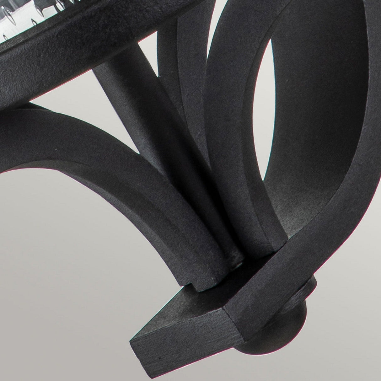 Close-up of the Merrill 1 Light Small Outdoor Wall Lantern in black, featuring curved, overlapping metal bars and a rectangular base set against a light gray background.