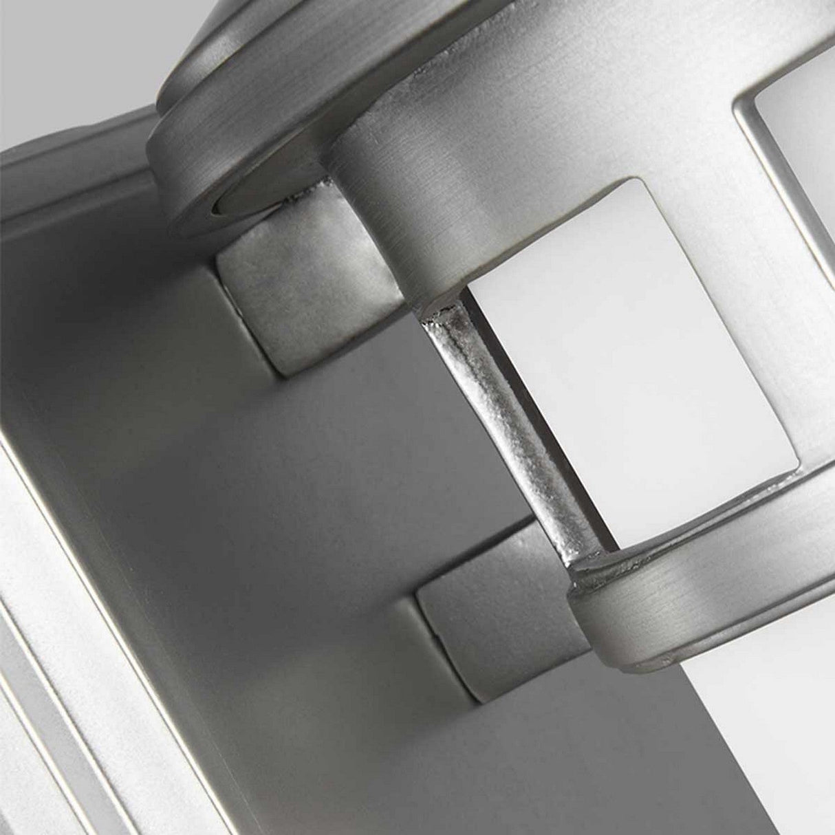 Close-up of the Newport 1 Light Outdoor Small Wall Lantern, featuring a sleek, angular design and a brushed steel finish. The image emphasizes the structure of this outdoor wall lantern, showcasing its modern and minimalistic aesthetic that exudes coastal elegance against a subtle background.