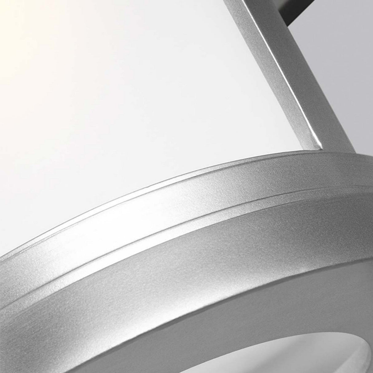 Close-up of the Newport 1 Light Outdoor Small Wall Lantern in brushed steel, featuring a sleek, curved silver design with a frosted glass surface that emits a soft glow. The image highlights the fixture's contemporary style and smooth finish, embodying coastal elegance.