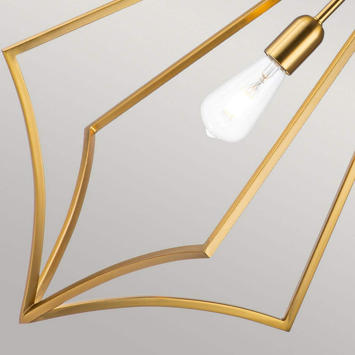 The Nico 1 Light Large Pendant in Burnished Brass is a modern chandelier featuring geometric artistry with a burnished brass frame and an exposed light bulb. Its design showcases angular lines that create a sophisticated, elegant look against a plain background.