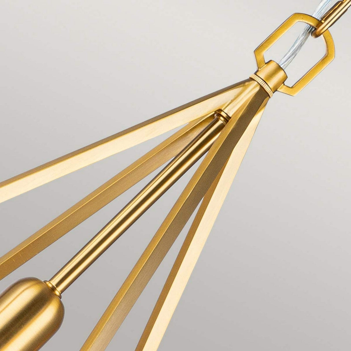 Close-up of the Nico 1 Light Medium Pendant in burnished brass, featuring a modern geometric design that exudes industrial charm. The fixture showcases intersecting rods connected by a hexagonal element at the top, set against a neutral background.