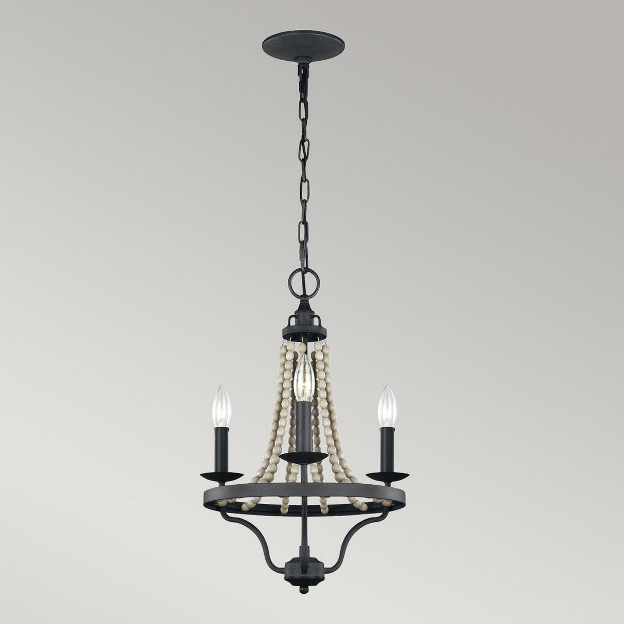 Introducing the Nori 3 Light Chandelier - Dark Weathered Zinc With Driftwood Grey, a vintage-style masterpiece. This elegant fixture showcases three candle-shaped bulbs on a black metal frame, embellished with decorative white beads and complemented by a Dark Weathered Zinc finish, all elegantly suspended against a Driftwood Grey backdrop.