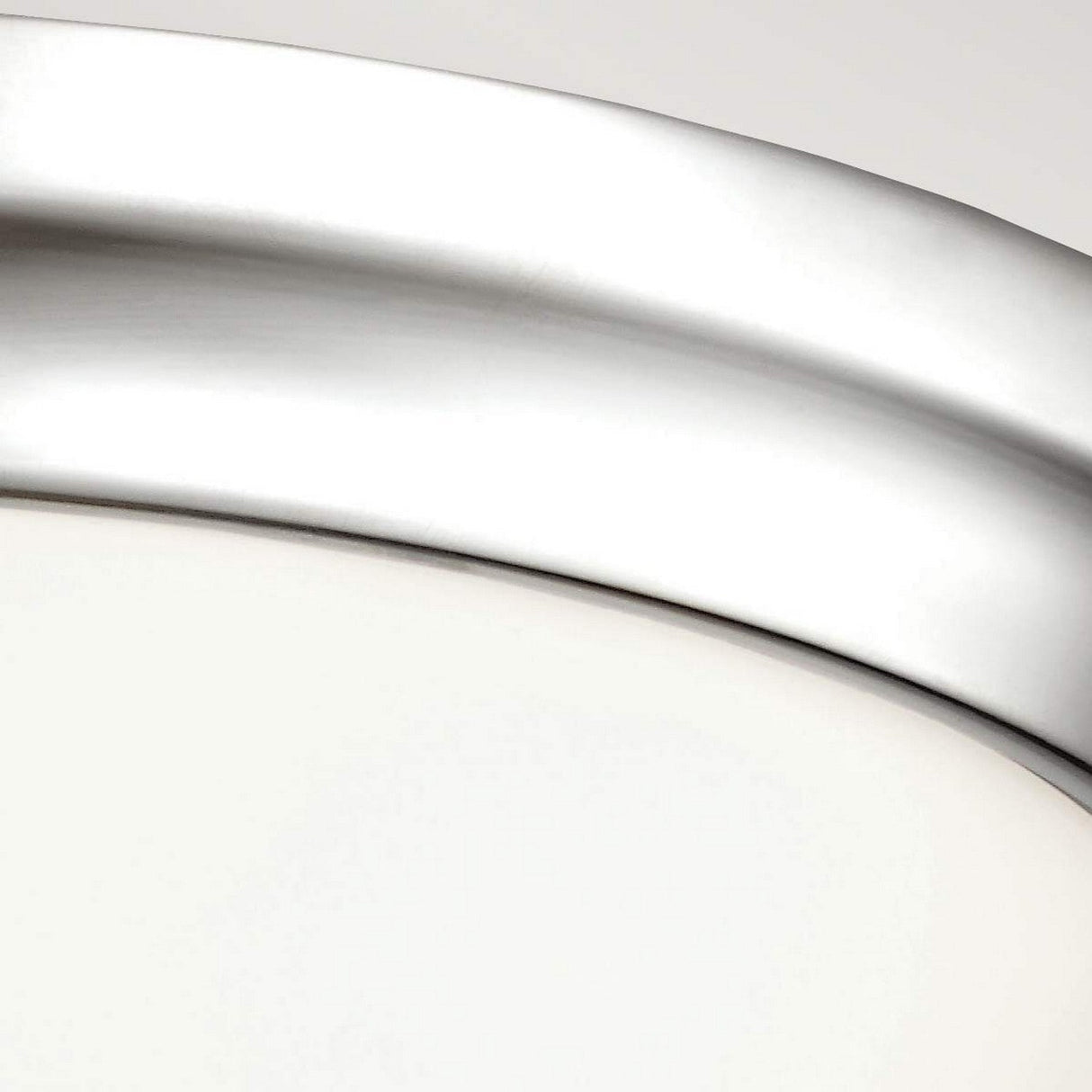 Close-up of a sleek, curved metallic surface with a smooth texture, catching the light. The object seems to be a section of a circular shape, likely the Parkman 2 Light Flush in polished nickel finish, placed against a neutral backdrop showcasing minimalist design.