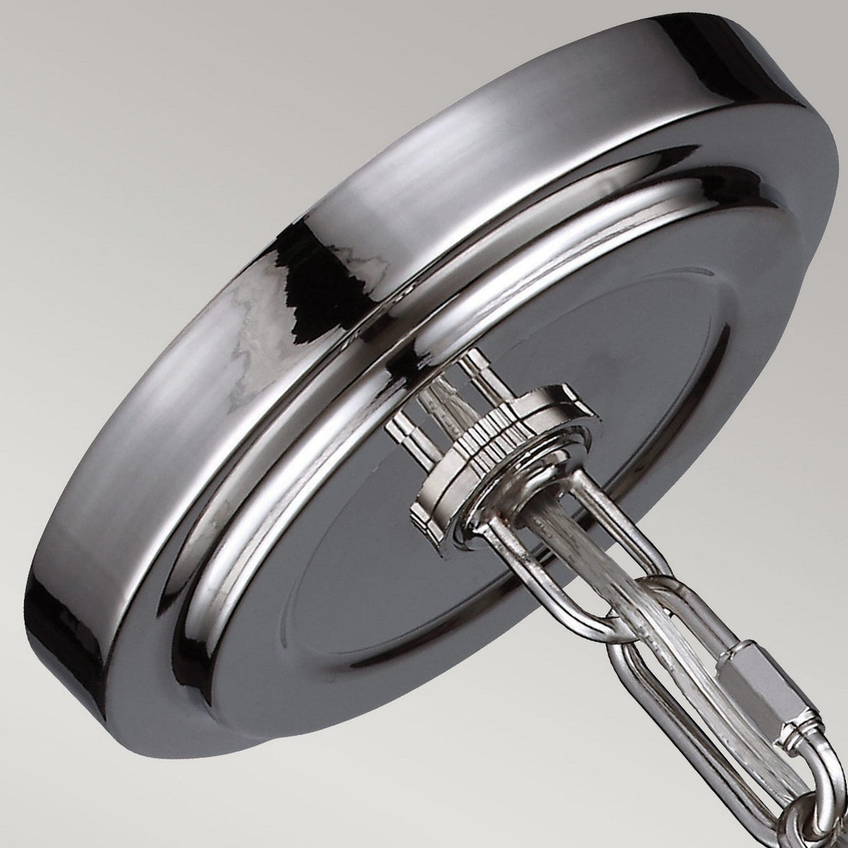 The spotlight is on the Parkman 1 Light Small Pendant in polished nickel, featuring a sleek, circular metallic design connected to a chain-like structure. Its reflective surface gleams with a smooth finish, beautifully complementing the plain gradient background transitioning from light gray to darker gray for a modern aesthetic.