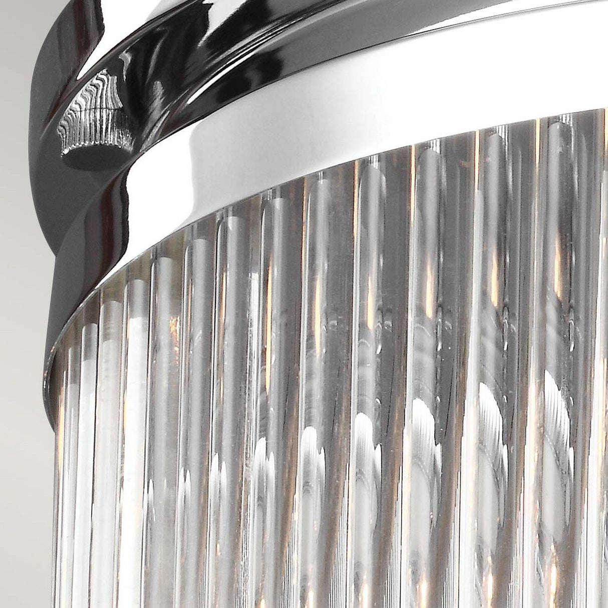 The image features a close-up of the Paulson 2 Light Flush - Chrome, highlighting the sleek chrome finish and cylindrical glass rods crafted in an art deco style. The picture accentuates the reflective and translucent qualities of these materials.