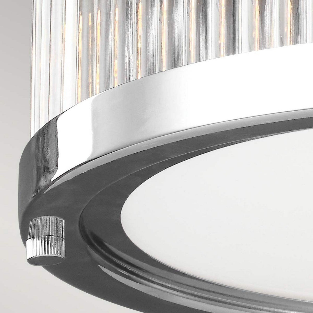 A close-up of the Paulson 2 Light Flush - Chrome showcases its modern design with a circular chrome-finished frame. The flush mount fixture features vertical glass rods adorning the top and a flat, white diffuser on the bottom, presenting an elegant and sleek appearance.