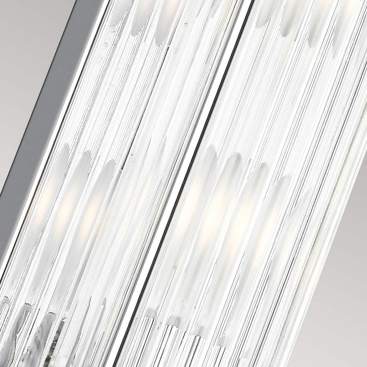 A close-up view of the Paulson 4 Light Bar Light - Chrome showcases its modern design, featuring parallel rows of thin, transparent rods that encase bright white lights. The sleek design and chrome elements contribute to an elegant and contemporary appearance.