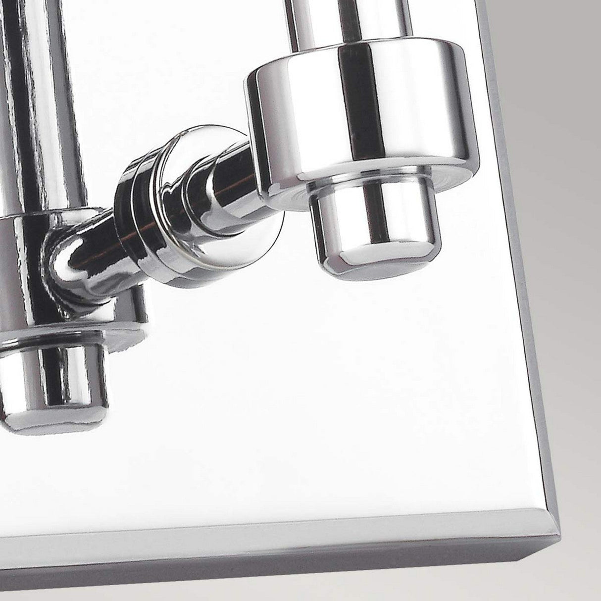 Close-up of a chrome-finished mechanical component with cylindrical shapes and reflective surfaces, reminiscent of the sleek Paulson 1 Light Wall Light in Chrome, set against a light gray background.