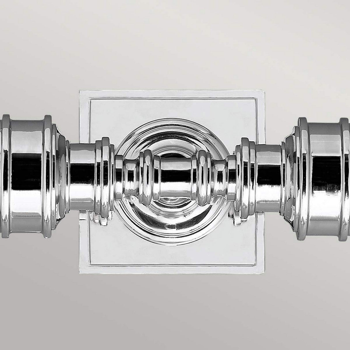Close-up of the Payne-1 polished chrome finish wall light, featuring an ornate, symmetrical design mounted on a square backplate against a light background.