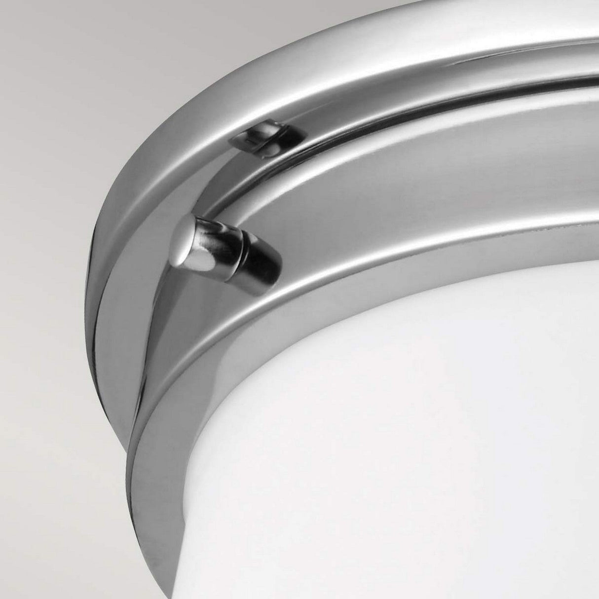 Close-up of the Payne 2 Light Flush - Polished Chrome, a modern ceiling light fixture featuring a sleek chrome frame with a frosted glass cover. The IP44-rated design boasts smooth, rounded edges and a metallic finish, set against a neutral background.