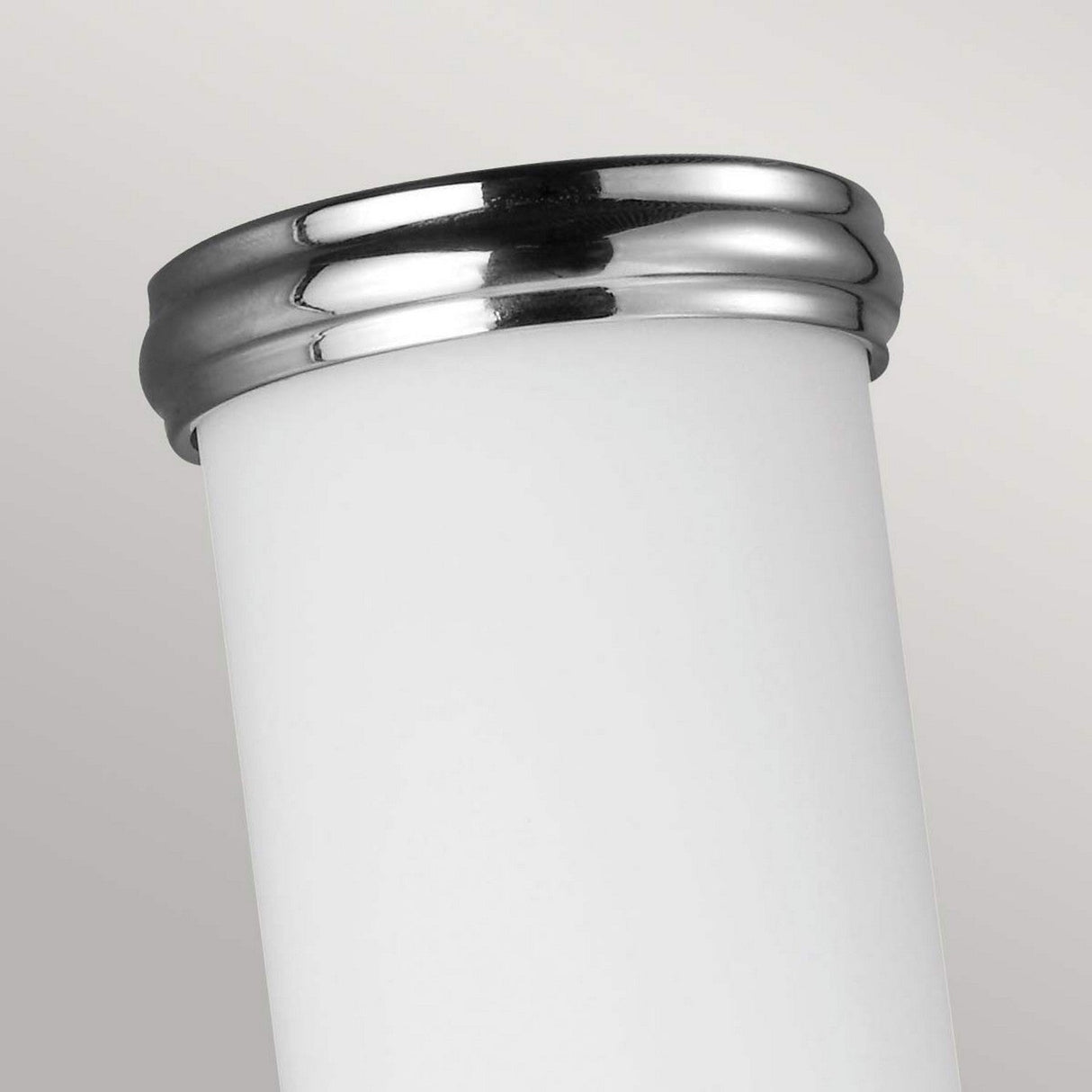 A close-up of the Payne-1 1 Light Wall Light - Polished Chrome against a light gray background. The sleek and modern design, resembling white opal etched glass, is highlighted by its shiny silver rim and smooth surface.