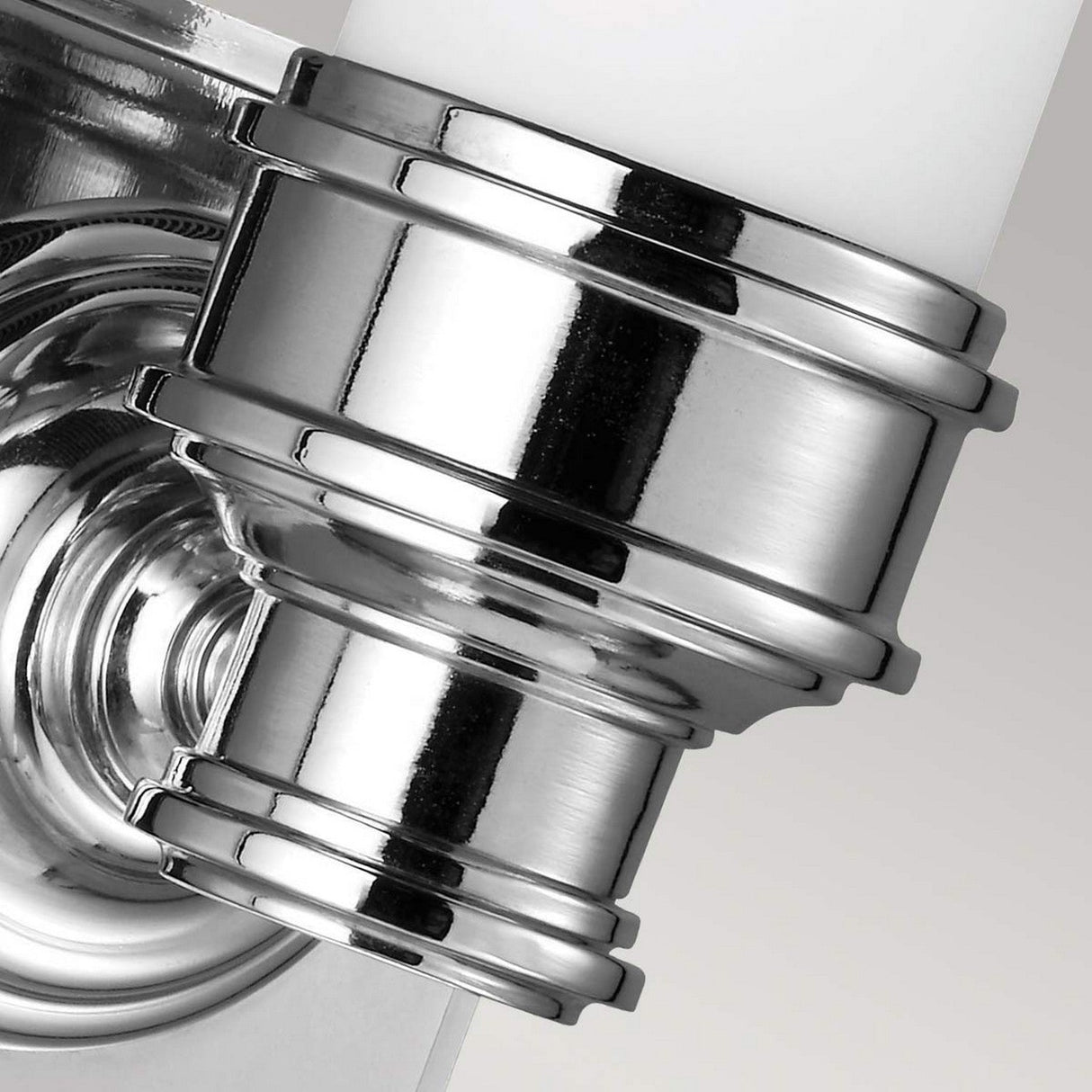 Close-up of the Payne-1 1 Light Wall Light, showcasing its metallic and shiny wall mount in a polished chrome finish. The design includes reflective surfaces with concentric rings and grooves, highlighting its industrial appearance against a plain background, making it an ideal complement to the sleekness of an IP44 rated fixture.