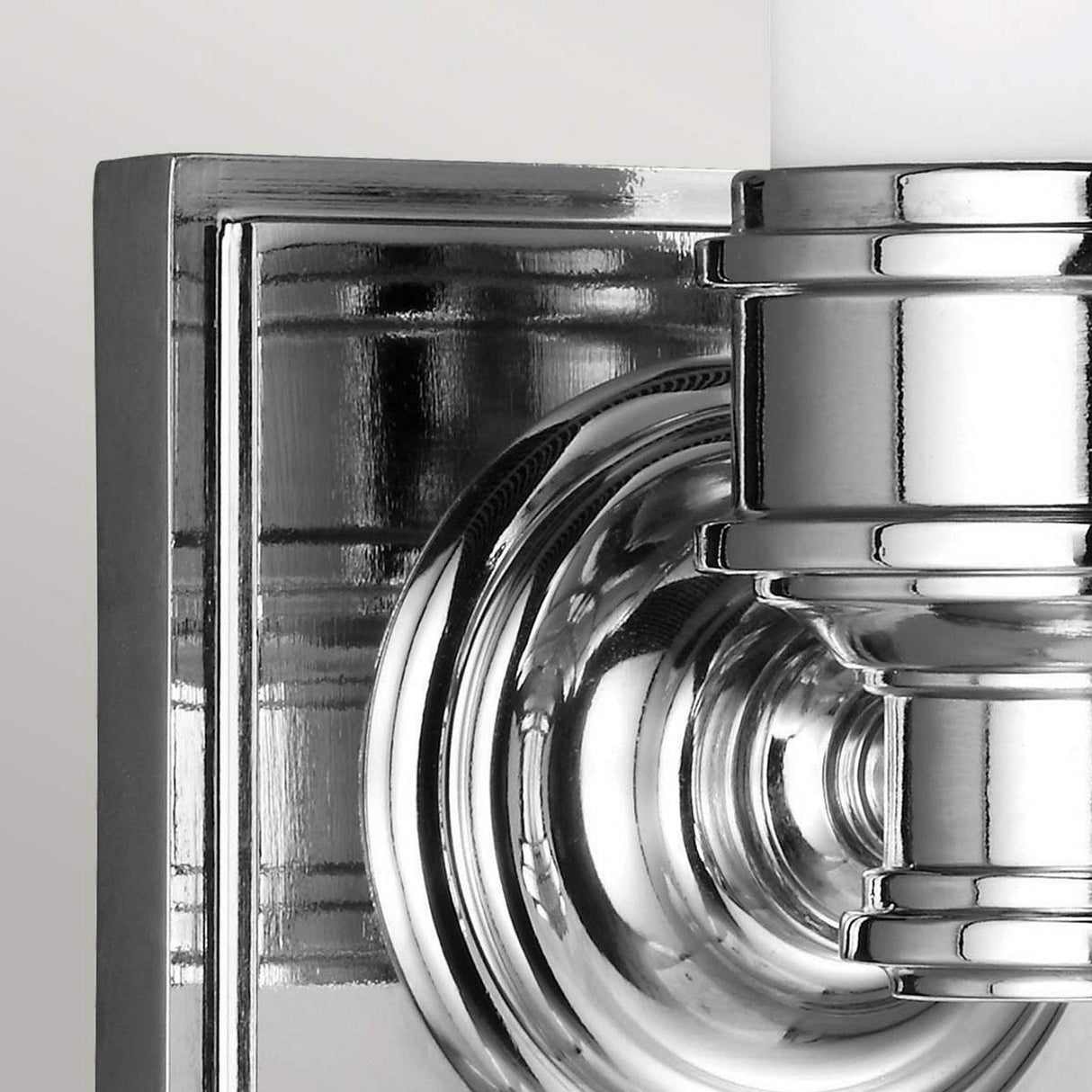 Close-up of the Payne-1 1 Light Wall Light, featuring a shiny, geometric design. The polished chrome finish beautifully reflects light, showcasing its intricate details and smooth surface.