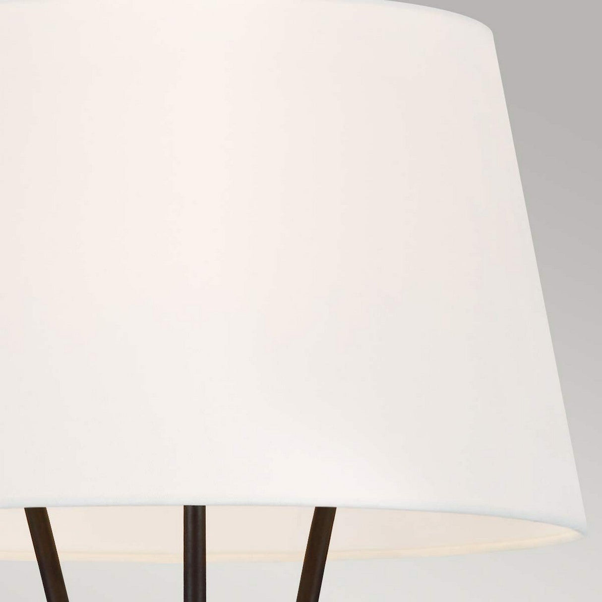 A close-up view of the Penny 1 Light Floor Lamp reveals a modern white linen lampshade with a smooth, slightly tapered shape. The minimalist design is elegantly paired with the black metal frame of the iron floor lamp, partially visible at the bottom, set against a neutral gray background.