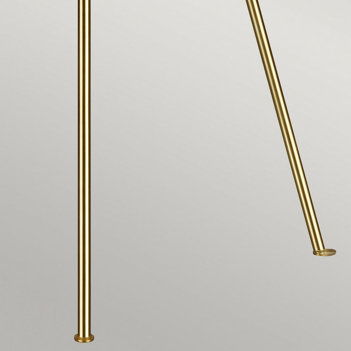 Against a simple grey backdrop, the Penny 1 Light Floor Lamp in Burnished Brass, with its two vertical rods each featuring small round bases, embodies mid-century elegance.