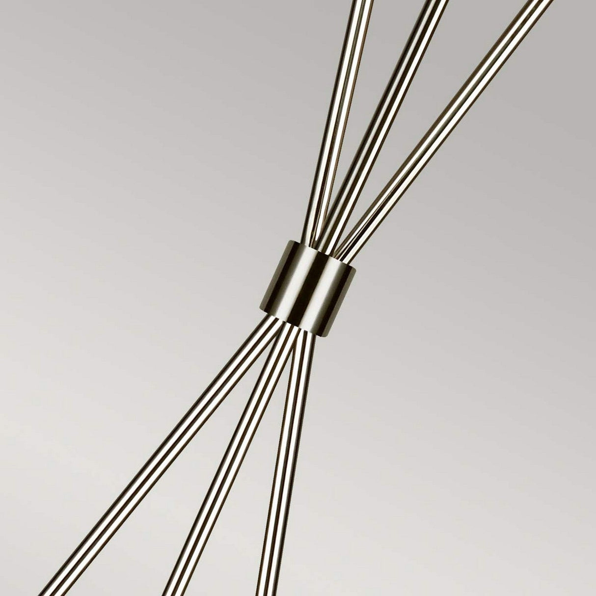 A close-up of the Penny 1 Light Floor Lamp in polished nickel highlights intersecting metal rods with a cylindrical connector at the center, all set against a simple background. This modern design showcases a symmetrical, geometric pattern that evokes sophistication.