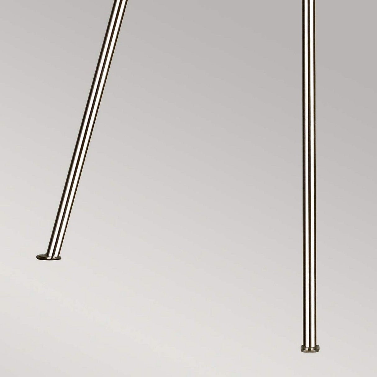 The Penny 1 Light Floor Lamp in polished nickel features two long, metallic poles angled inward against a simple, light gray background, embodying modern design.