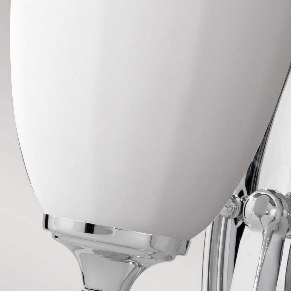 Close-up of the Perry 1 Light Wall Light in polished chrome, showcasing its opal glass shade. The sleek and minimalistic design makes it an ideal bathroom light for reflecting a contemporary style.