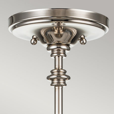 A close-up of the Pickering Lane 3 Light Semi Flush in polished nickel showcases its round base adorned with decorative knobs and a sleek, elegant design. The metal's shiny finish beautifully reflects light, infusing a modern touch into this semi-flush piece that harmoniously combines contemporary style with farmhouse lighting charm.