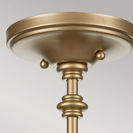 Close-up image of the Pickering Lane 3 Light Semi Flush in brass, featuring a round canopy and decorative rod. The design exudes vintage charm with its smooth, rounded shapes and simple elegance, enhanced by the backdrop of a light gray background.