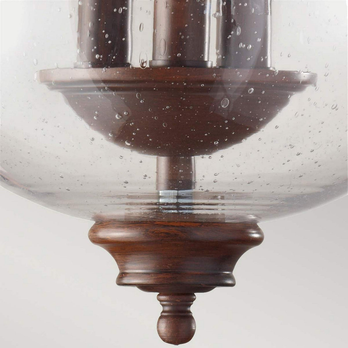 Close-up of the Pickering Lane 3 Light Semi Flush featuring a vintage-style design with a wooden base and clear, seeded glass shade. The speckled bubbles infuse rustic charm, while the bronze finish beautifully complements the candle-style bulbs visible through its enchanting globe.