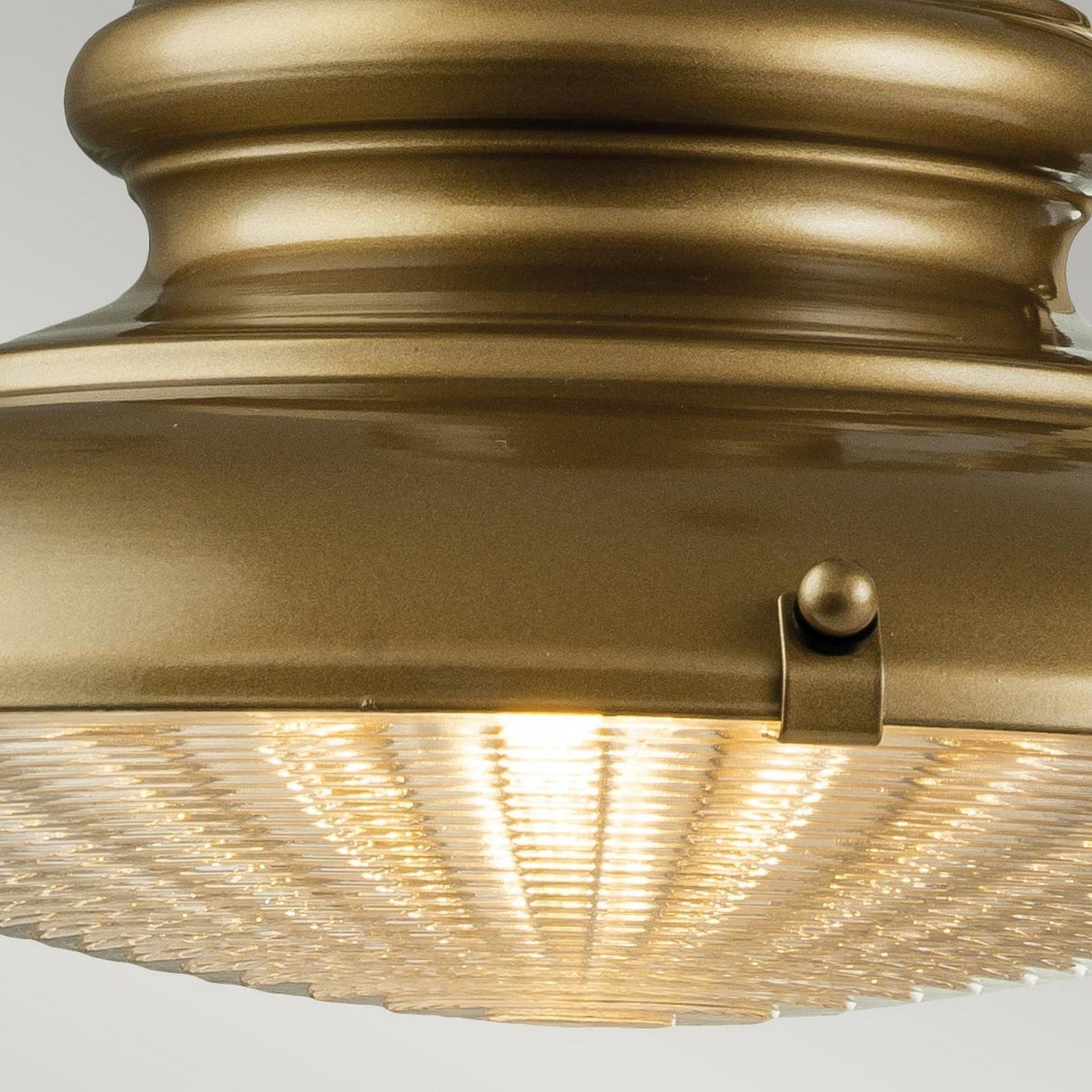 Close-up of a vintage Redding Station 1 Light Outdoor Medium Wall Lantern in bronze, featuring a ribbed glass cover that is softly illuminated. The design exudes timeless elegance with its classic and sophisticated appearance.