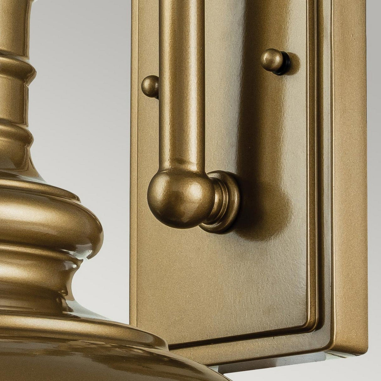 Close-up of the Redding Station 1 Light Outdoor Medium Wall Lantern in bronze, featuring a smooth cylindrical design with vintage appeal. The light fixture showcases a shiny, polished finish and detailed craftsmanship, highlighted by its sturdy build and elegant metallic luster against a neutral background.