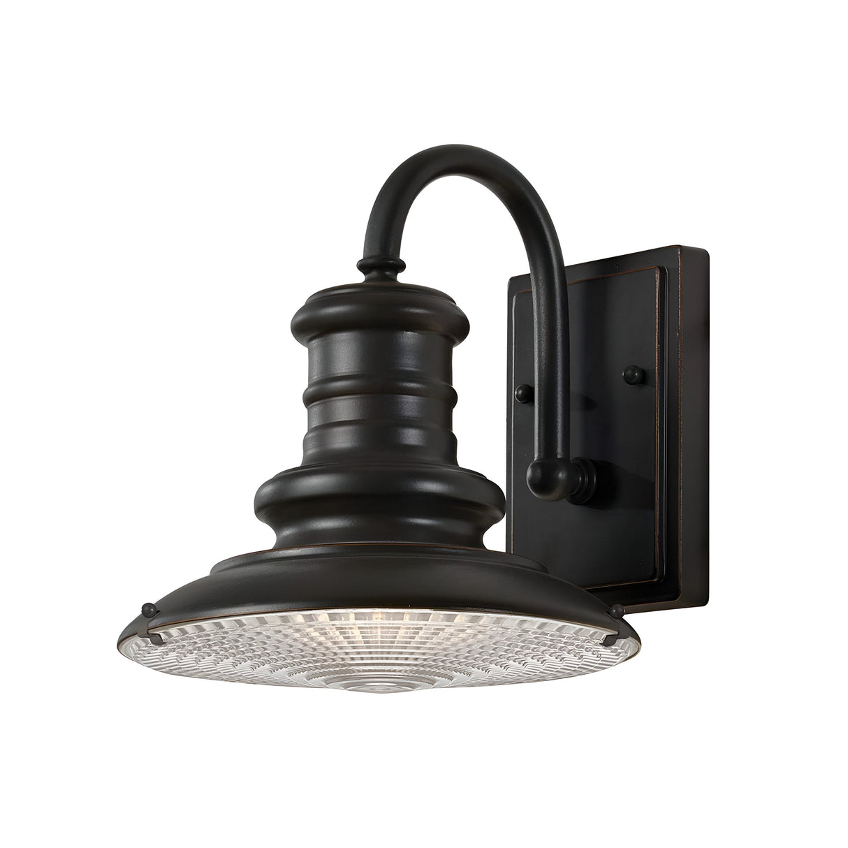 The Redding Station 1 Light Outdoor Small Wall Lantern in Dark Bronze features a vintage-style design with a curved arm and detailed prismatic glass shade, mounted on a rectangular backplate. Its dark bronze finish enhances its charm as it emits a warm glow.