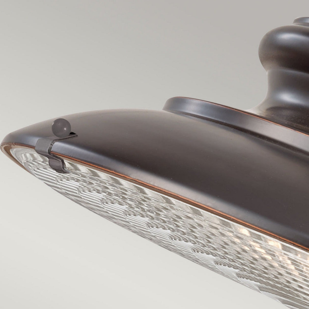 Close-up of the Redding Station 1 Light Outdoor Medium Chain Lantern in a dark bronze finish, showcasing its prismatic glass diffuser. The lantern features a round, domed shape with subtle decorative accents on the surface, set against a neutral gray background.