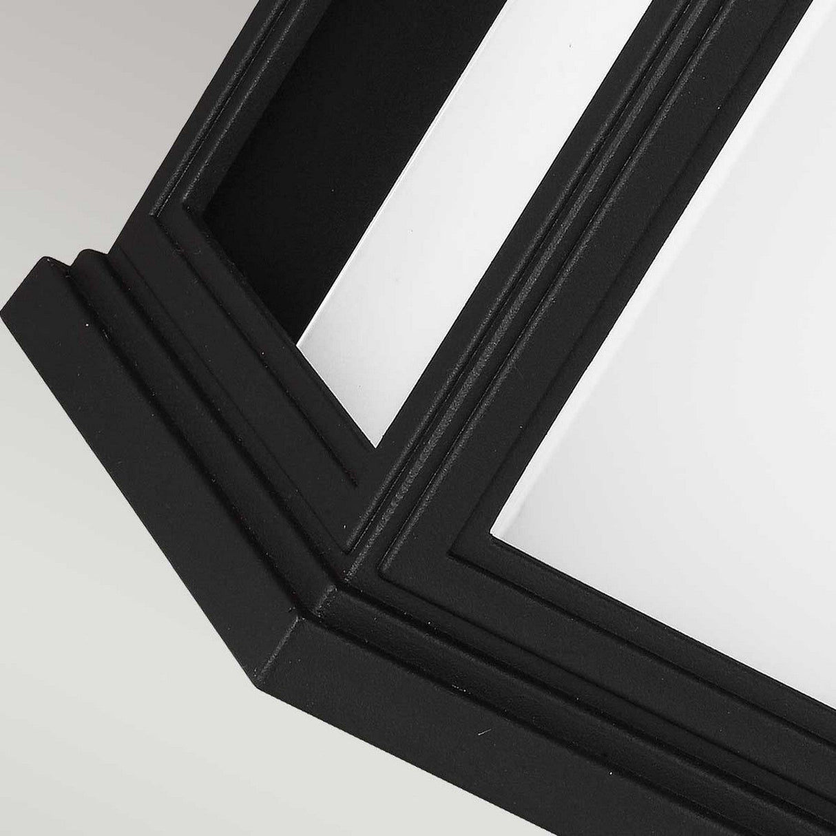 A close-up view of the Roscoe 1 Light Outdoor Large Wall Lantern in black showcases its matte finish with angular, sharp edges against a light background. The design features intersecting lines and a grid-like pattern, giving it a modern and abstract look.