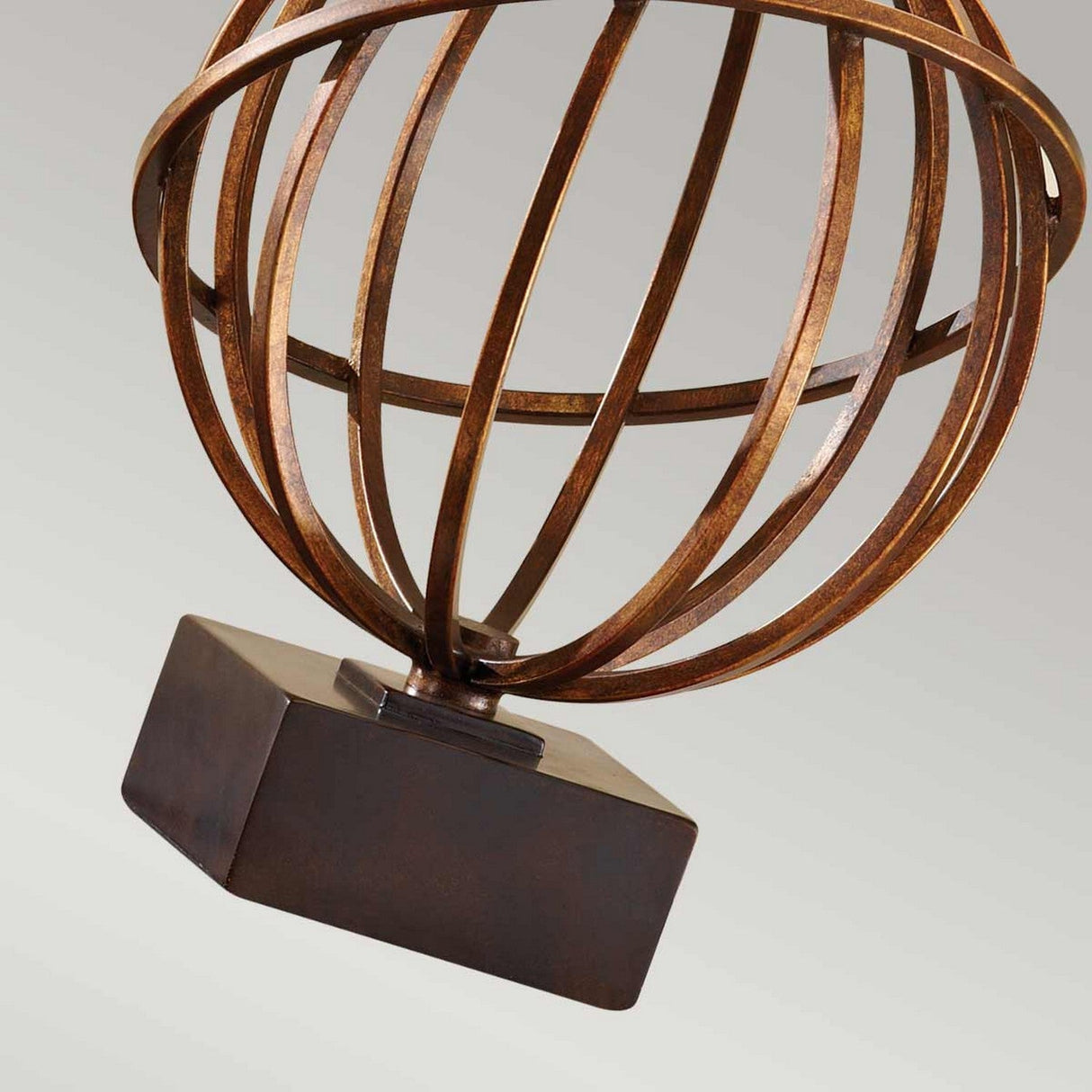 The Spencer 1 Light Table Lamp in a Firenze Gold finish features a bronze-colored spherical metal globe structure with intersecting rings, elegantly mounted on a dark walnut base, all set against a light gray background.