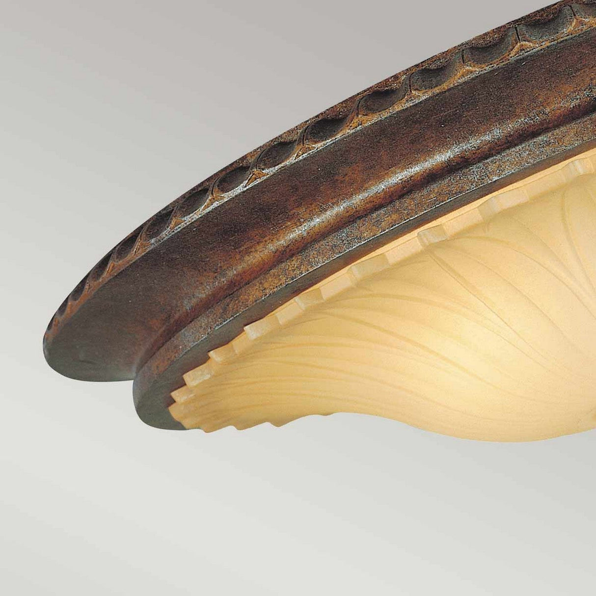 Close-up of the Stirling Castle 2 Light Flush - Bronze, showcasing its decorative flush mount design with a circular, textured metallic rim and a frosted glass shade adorned with an elegant, swirling pattern. The warm lighting casts an inviting glow against a neutral background, evoking the charm of Gothic arch design.