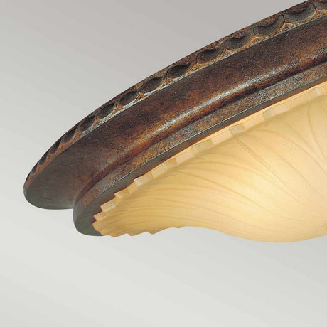 Close-up of the Stirling Castle 2 Light Flush - Bronze, showcasing its decorative flush mount design with a circular, textured metallic rim and a frosted glass shade adorned with an elegant, swirling pattern. The warm lighting casts an inviting glow against a neutral background, evoking the charm of Gothic arch design.