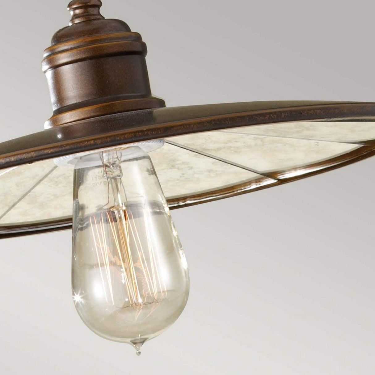 A close-up of the Urban Renewal 1 Light Pendant in bronze showcases its vintage charm. The metal frame paired with an Edison-style bulb offers a striking appearance, as the bulb encased in transparent glass highlights intricate filament details. The rustic bronze finish completes the fixture against a neutral background.