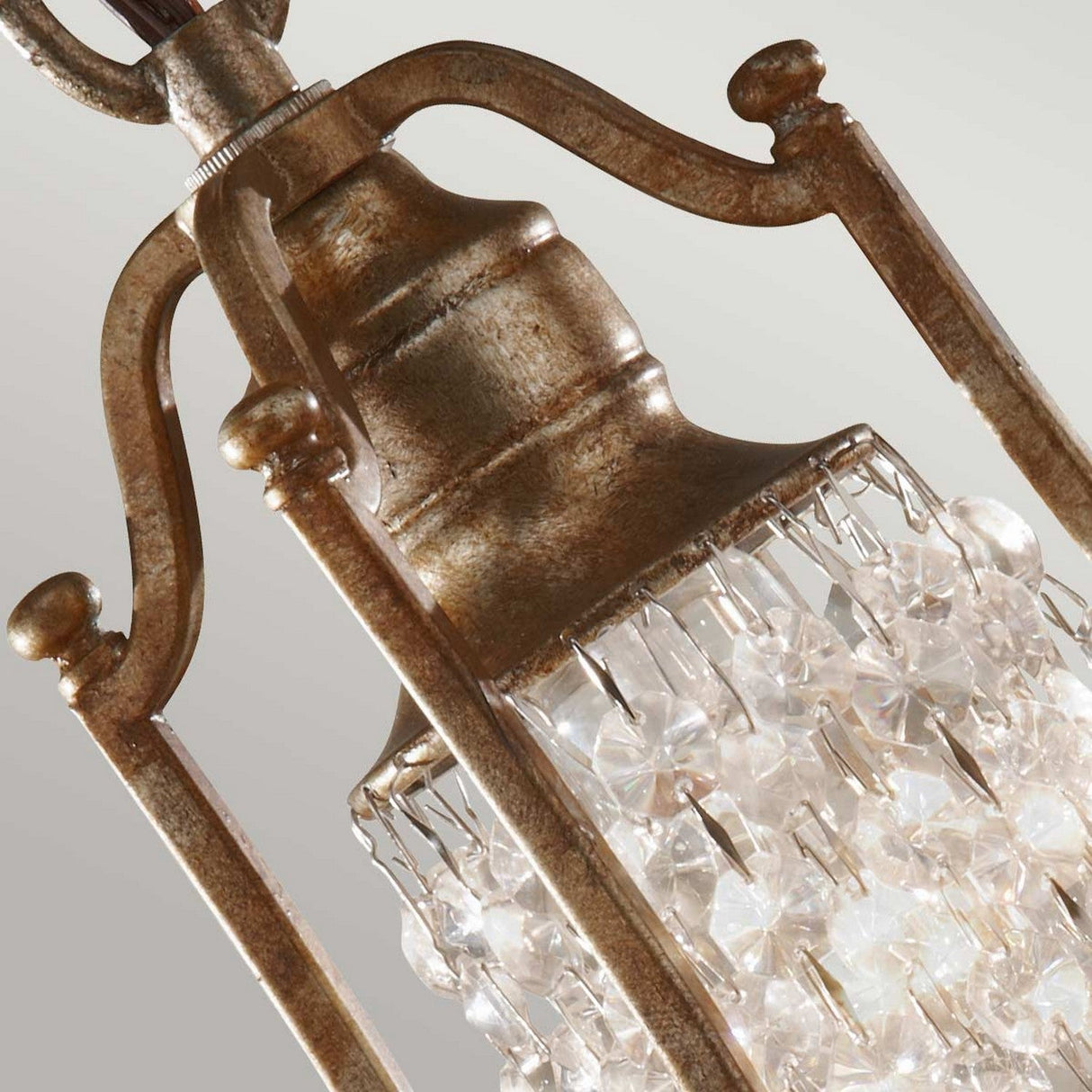 A close-up view of the Valentina 1 Light Mini Pendant showcases its vintage-style design, featuring an oxidized bronze frame adorned with cascading clear crystal beads. Set against a light gray background, the crystals are elegantly arranged in a cylindrical shape and enhanced by crystal bobeche accents, lending a classic touch to this exquisite fixture.